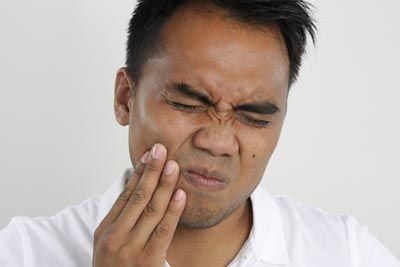 man holding his mouth in pain